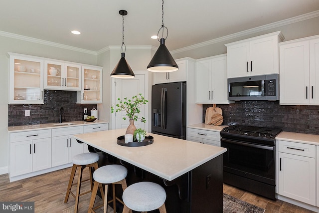 kitchen featuring hanging light fixtures, dark hardwood / wood-style flooring, a breakfast bar area, black appliances, and tasteful backsplash