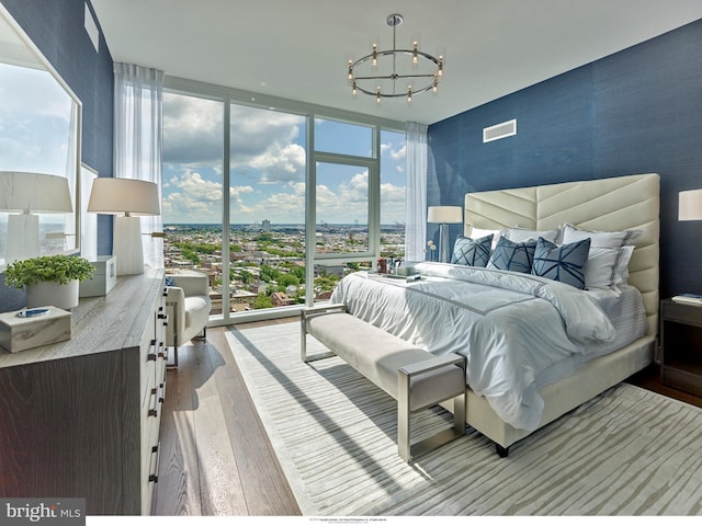 bedroom with an inviting chandelier, a wall of windows, multiple windows, and light wood-type flooring