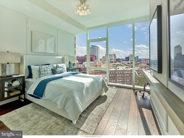 bedroom with a chandelier, hardwood / wood-style flooring, and a wall of windows