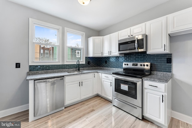 kitchen with white cabinets, tasteful backsplash, sink, and stainless steel appliances