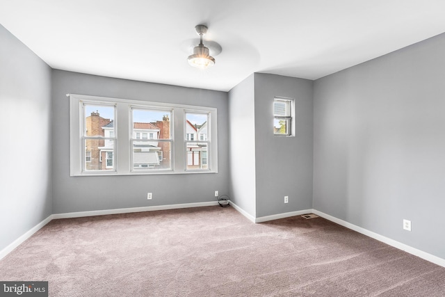 carpeted spare room featuring ceiling fan and a wealth of natural light