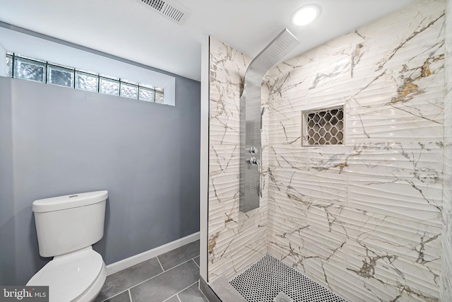 bathroom featuring a tile shower, tile flooring, and toilet