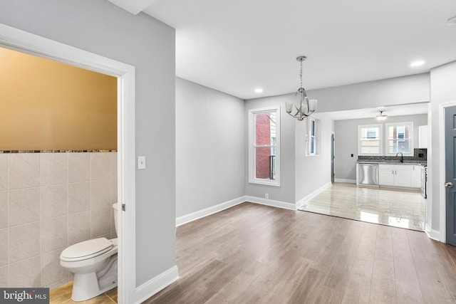 interior space featuring plenty of natural light, tile walls, toilet, and vanity with extensive cabinet space