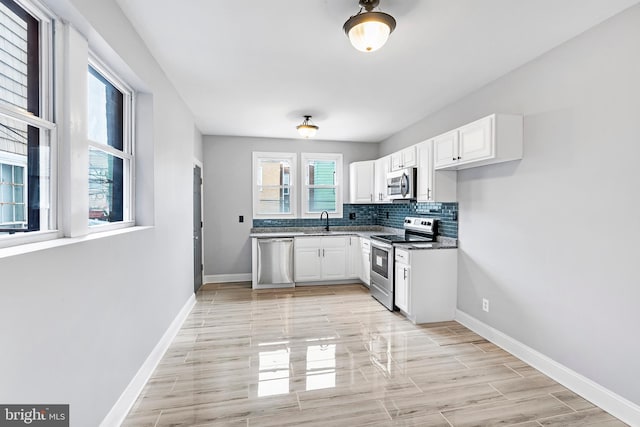 kitchen featuring sink, stainless steel appliances, backsplash, and white cabinets