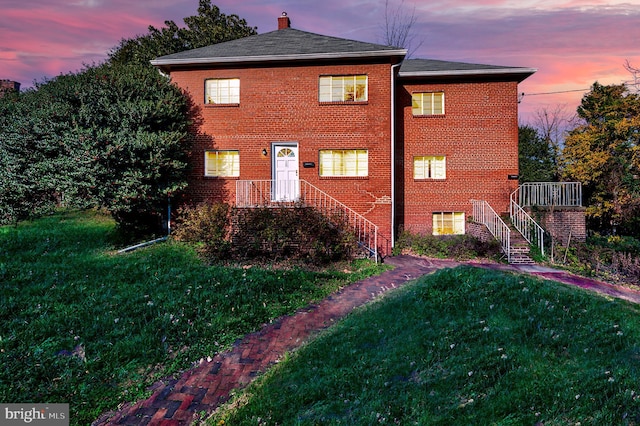 property exterior at dusk featuring a yard