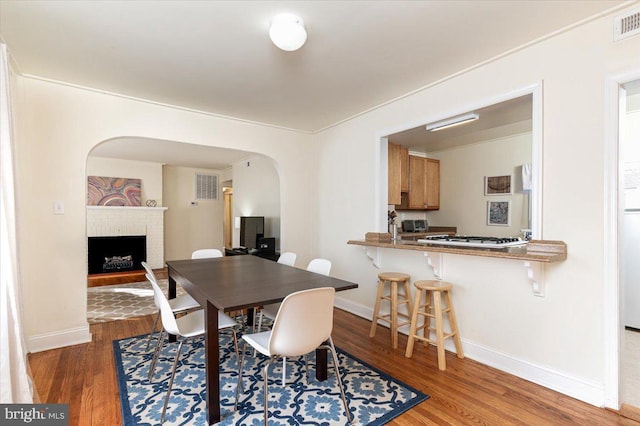 dining space featuring dark hardwood / wood-style floors and a brick fireplace