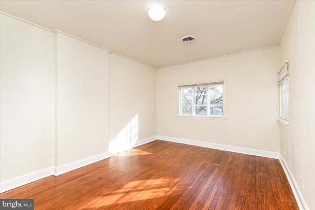 spare room featuring dark wood-type flooring and ornamental molding