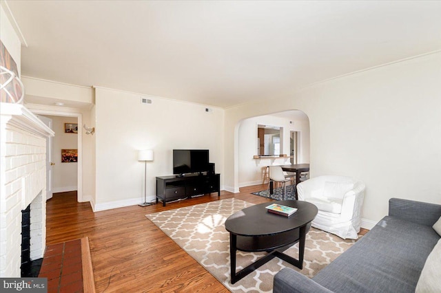 living room featuring a fireplace, ornamental molding, and hardwood / wood-style flooring