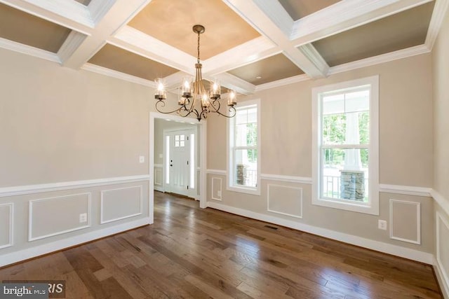 unfurnished room with an inviting chandelier, coffered ceiling, crown molding, and dark wood-type flooring