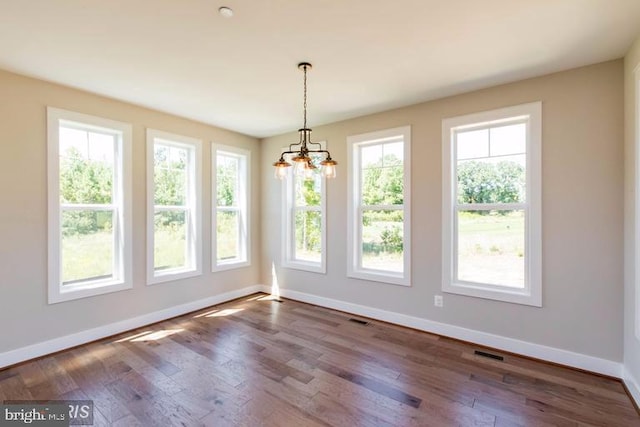 spare room featuring dark hardwood / wood-style floors and a chandelier