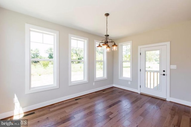 unfurnished dining area featuring a notable chandelier and dark wood-type flooring