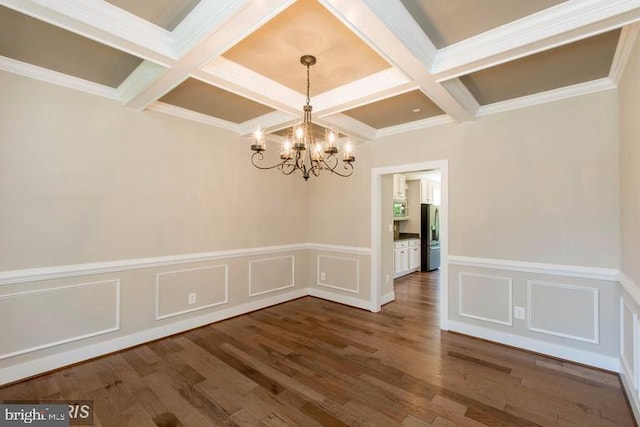 spare room with an inviting chandelier, beam ceiling, coffered ceiling, ornamental molding, and dark hardwood / wood-style floors