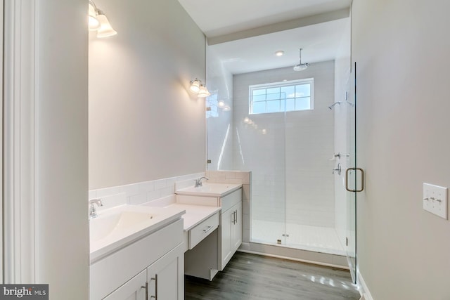 bathroom featuring tile walls, wood-type flooring, backsplash, dual vanity, and an enclosed shower