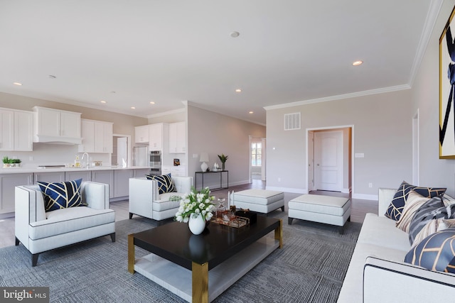 living room featuring ornamental molding, hardwood / wood-style flooring, and sink