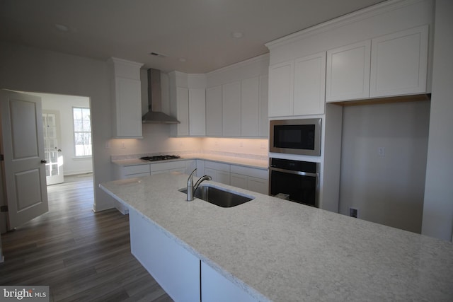 kitchen featuring dark wood-type flooring, white cabinets, sink, wall chimney exhaust hood, and appliances with stainless steel finishes