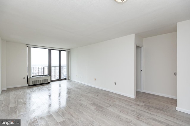 empty room with radiator heating unit and light wood-type flooring