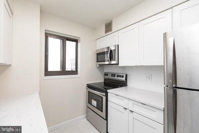 kitchen featuring white cabinets, backsplash, appliances with stainless steel finishes, and light stone counters