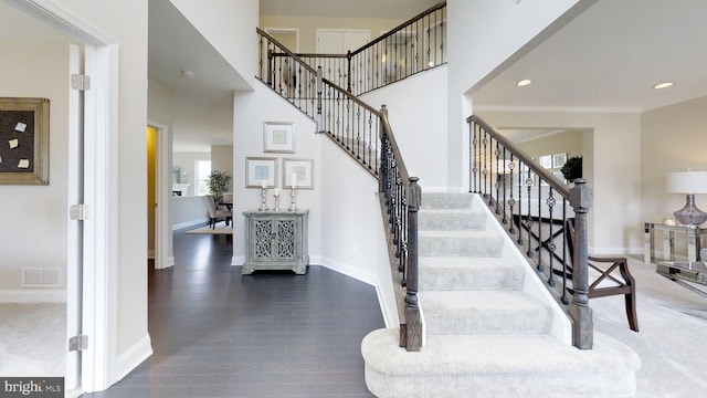 stairs featuring a high ceiling and dark hardwood / wood-style flooring