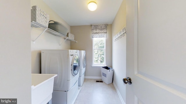 laundry area featuring washing machine and dryer, light tile floors, and sink