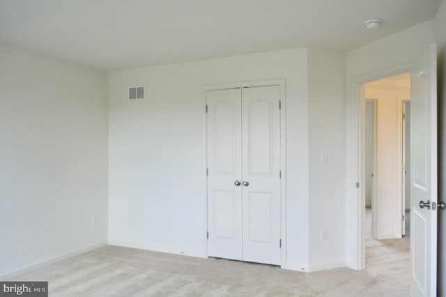 unfurnished bedroom with a closet and light colored carpet