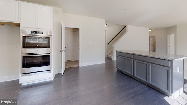 kitchen featuring double oven, light stone countertops, gray cabinets, white cabinets, and dark hardwood / wood-style floors