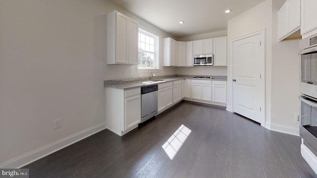 kitchen featuring sink, dark hardwood / wood-style flooring, stainless steel appliances, light stone countertops, and white cabinetry