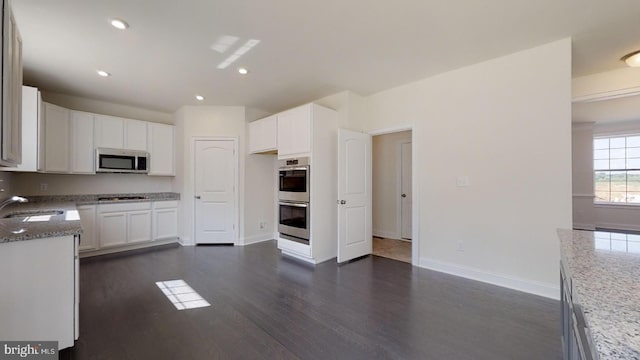 kitchen featuring dark stone counters, white cabinetry, dark wood-type flooring, and appliances with stainless steel finishes