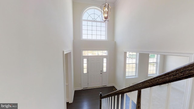 entryway with dark hardwood / wood-style flooring, a notable chandelier, and a high ceiling