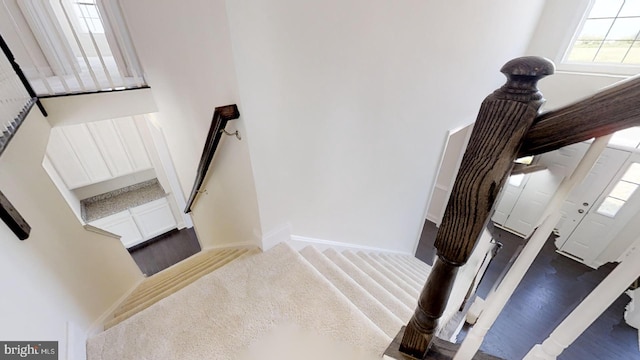 stairs featuring dark carpet and a towering ceiling