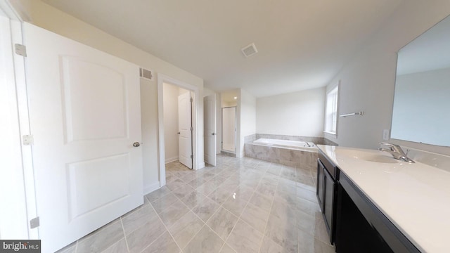 bathroom featuring tile floors, large vanity, and tiled tub