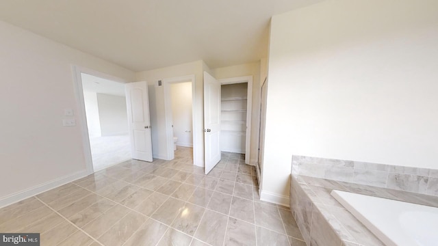 bathroom with tile flooring and tiled bath