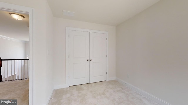 unfurnished bedroom with light carpet and a closet