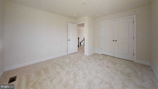 unfurnished bedroom featuring a closet and light colored carpet