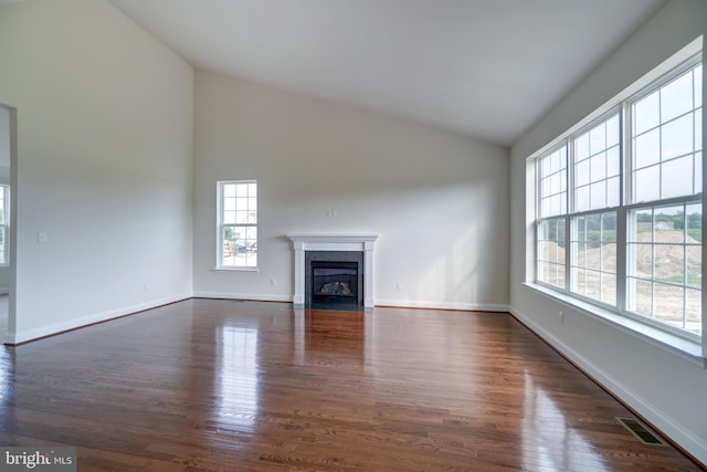 unfurnished living room with high vaulted ceiling and dark hardwood / wood-style flooring