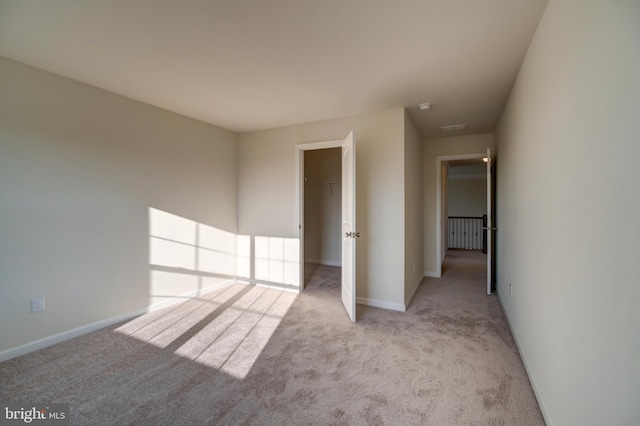 unfurnished bedroom with light carpet, a closet, and a walk in closet