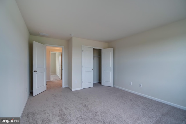 unfurnished bedroom featuring light colored carpet and a closet