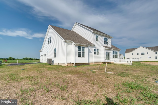 rear view of house with central AC unit and a yard