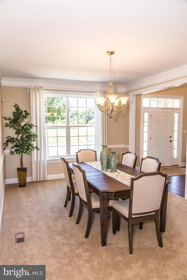 carpeted dining space featuring ornamental molding and a notable chandelier