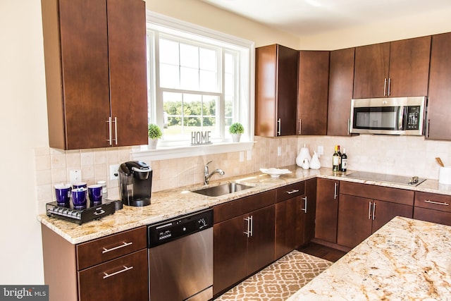 kitchen featuring appliances with stainless steel finishes, light stone counters, tasteful backsplash, and sink