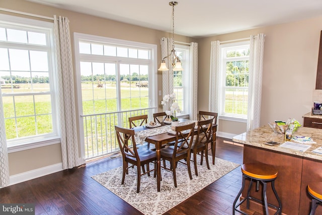 dining space featuring a healthy amount of sunlight, an inviting chandelier, and dark hardwood / wood-style flooring