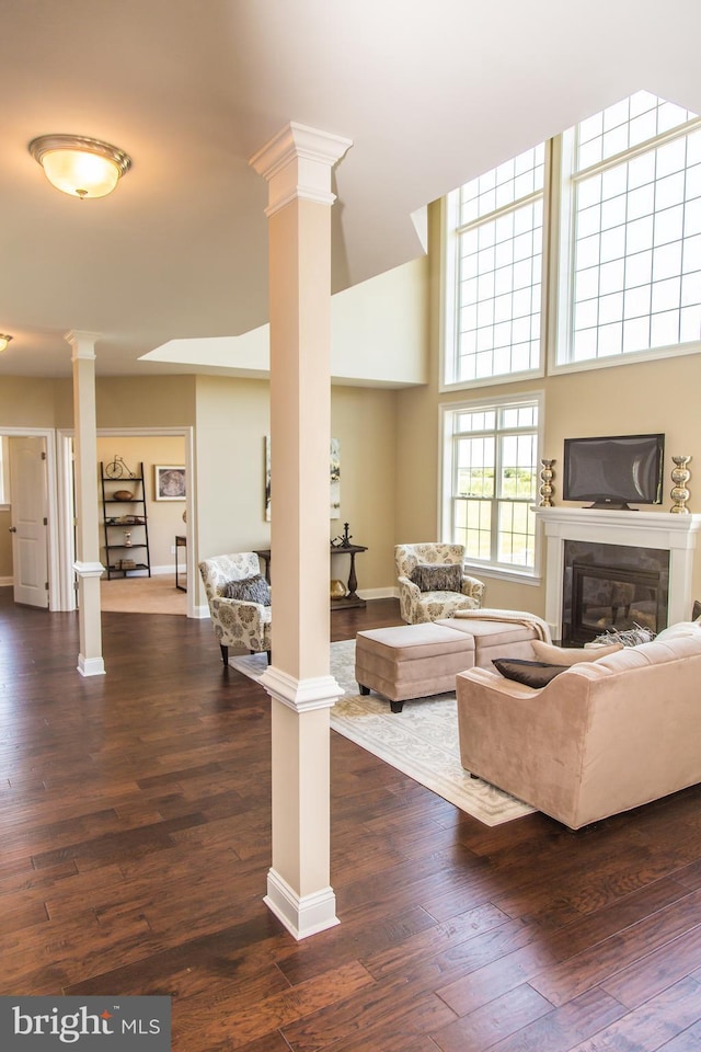 living room with a high ceiling, dark hardwood / wood-style floors, and ornate columns