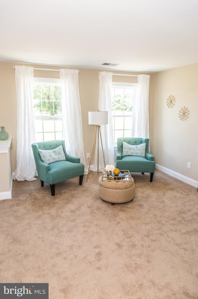 living area with a healthy amount of sunlight and light colored carpet