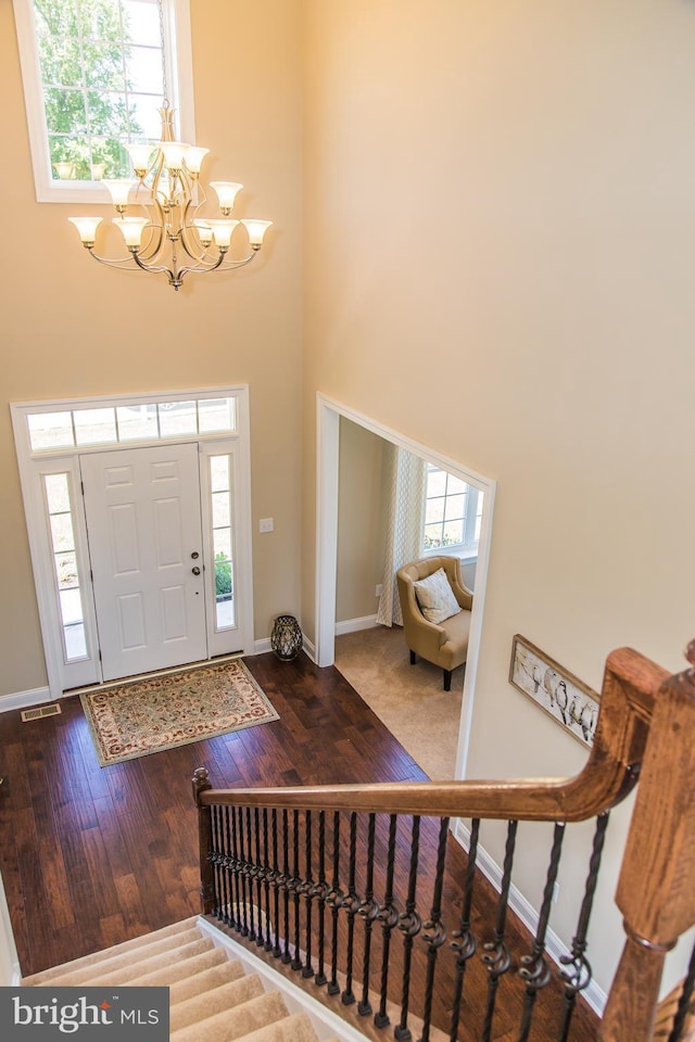 entrance foyer featuring light hardwood / wood-style floors, a healthy amount of sunlight, a chandelier, and a towering ceiling