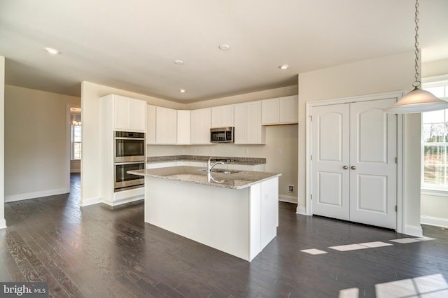 kitchen featuring a center island with sink, stainless steel appliances, white cabinetry, and dark wood-type flooring