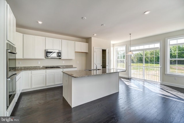 kitchen featuring a kitchen island with sink, appliances with stainless steel finishes, white cabinets, dark hardwood / wood-style flooring, and pendant lighting