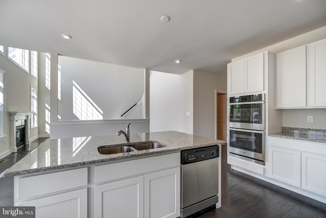 kitchen featuring stainless steel appliances, dark hardwood / wood-style flooring, sink, white cabinetry, and light stone countertops