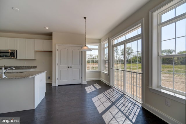 kitchen featuring decorative light fixtures, white cabinetry, dark hardwood / wood-style floors, and plenty of natural light