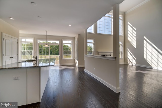 kitchen featuring hanging light fixtures, dark wood-type flooring, sink, dark stone countertops, and a chandelier