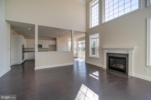 unfurnished living room featuring a high ceiling, dark hardwood / wood-style floors, and a fireplace