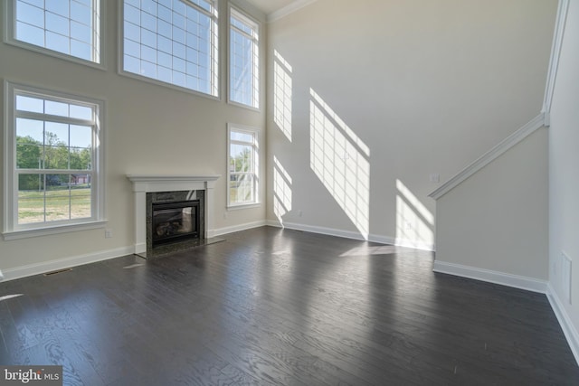 unfurnished living room featuring dark wood-type flooring, a premium fireplace, and plenty of natural light